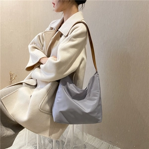 Detailed view of lavender shoulder bag with brown strap on a beige coat outfit