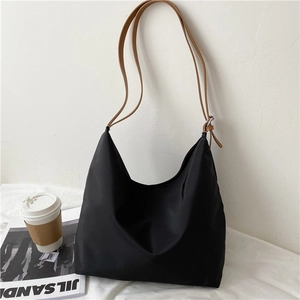 Detail of black nylon hobo bag with brown leather straps and metal buckles for commuting