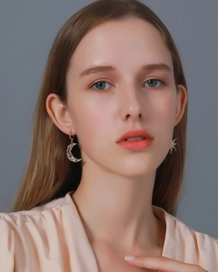 Close-up of golden sun and moon earrings worn by model with abstract hollowed patterns
