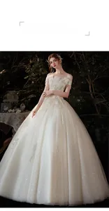 Détail de la broderie de paillettes et plumes sur une robe de mariée champagne à épaules nues