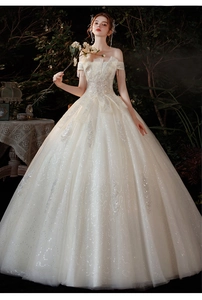 Détail d'une robe de mariée à épaules dénudées avec paillettes et broderies plumes