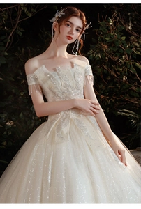 Détail d'une robe de mariée à épaules dénudées avec broderie plumes et tulle scintillant