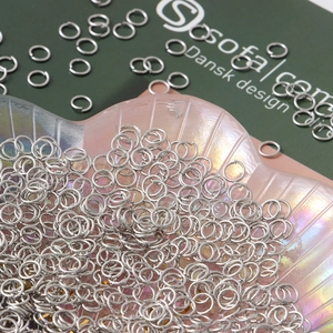 Polished silver jump rings for jewelry making displayed on a shell tray for DIY crafts
