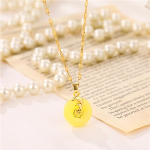 Elegant gold titanium necklace with amber dolphin pendant on a vintage book background