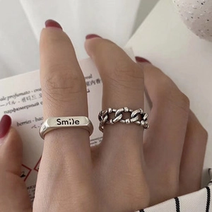 Primo piano dell'anello d'argento inciso Smile e dell'anello a catena sulle dita della modella