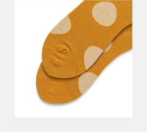 Macro detail of mustard yellow cotton knit socks with large beige polka dots pattern