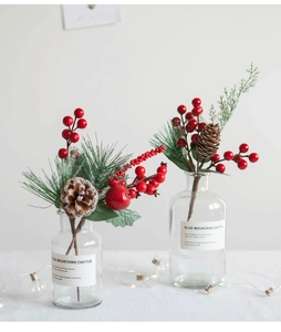 Close-up of Christmas red berries and pine cones in glass vase with fairy lights decoration