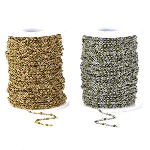 Detail of gold and silver DIY stainless steel chains with green enamel beads on spools