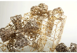 Dettaglio del pacco regalo natalizio dorato con paillettes lucide e perline preziose