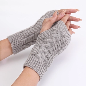 Close-up of grey cable-knit fingerless gloves showing thumb hole and ribbed cuff textures