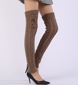 Detail of coffee brown cable knit leg warmers with pom-pom drawstrings on model