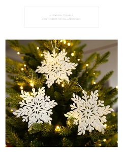 Close-up of a white glittery snowflake ornament hanging on a festive Christmas tree branch