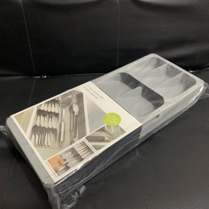 Close-up of the grey multi-compartment drawer cutlery organiser in plastic packaging