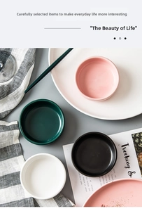 Overhead view of four colorful ceramic sauce dishes in matte pink, green, black, and white