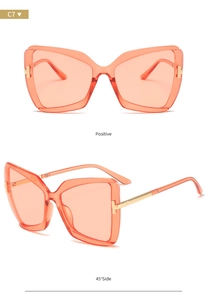 Detail view of orange butterfly sunglasses with gold T-shaped metal hinge and clear lenses