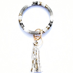 Macro detail of snake skin pattern wristlet keychain with gold ring and leather tassel