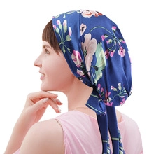 Detail shot of the adjustable tie design and pink floral print on a navy blue headscarf