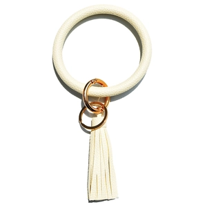 Detail of off-white lychee texture leather bangle keychain with tassel and gold hardware