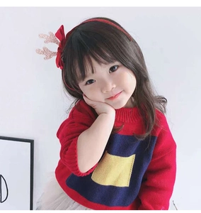 Detail of a red Christmas headband with cute glittery antlers and a plush bow on a young girl