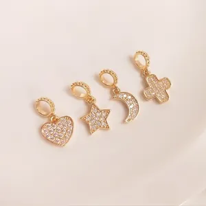 Macro view of gold plated 14K heart star moon and cross charms with pavé zircon stones