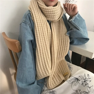 Detailed texture of thick beige knitted scarf with vintage Hand Made label and vertical ribbing