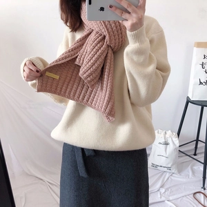 Detail of chunky ribbed knit scarf in pink-purple worn with cream sweater