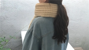 Detail of chunky beige knitted scarf showing thick horizontal ribbed texture on model