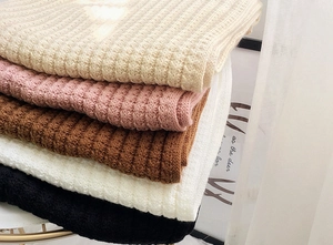 Close-up of thick knit winter scarves in multiple colors showing texture and soft material