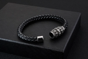 Close-up of black braided leather bracelet with skull-engraved silver magnetic clasp