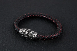 Close-up of black braided leather bracelet with red stitching and silver skull bead