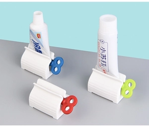 Set of three manual rolling toothpaste squeezers with colorful knobs on a modern background