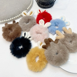 Flat lay of nine plush hair scrunchies with rabbit ears and reindeer antlers in varied colors