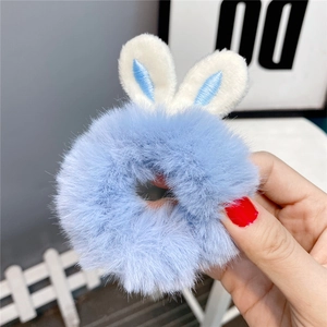 Detailed view of a soft blue plush hair scrunchie with cute white rabbit ears design