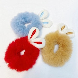 Close-up of plush rabbit ear hair ties in blue, red, and camel colors on a white background