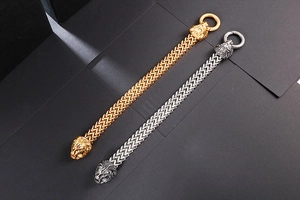 Detailed close-up of woven stainless steel bracelets with lion head reliefs in gold and silver
