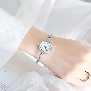 Close-up of a silver bangle watch with a quartz movement on a woman's wrist