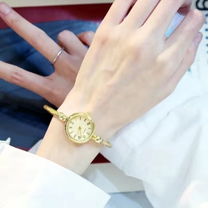 Dettaglio dell'orologio a bracciale dorato con quadrante romano bianco al polso