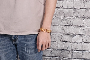 Detailed view of men's golden stainless steel dragon bracelet worn on the wrist