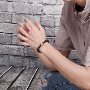 Bracelet pour hommes en perles de lave avec breloque crâne dorée au poignet masculin