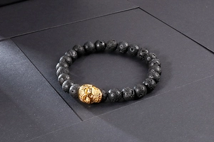 Détail macro de perles en pierre de lave noire et d'un crâne doré sur un bracelet
