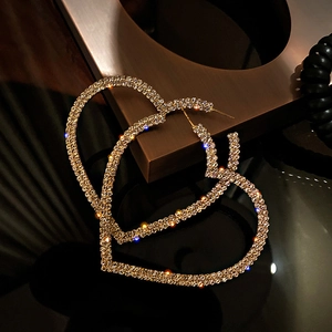 Macro shot of oversized heart hoop earrings encrusted with sparkling clear rhinestones
