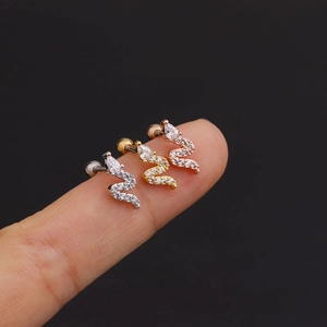Detailed comparison of snake cartilage studs in silver, gold, and rose gold on a finger