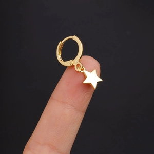 Detail of gold hoop earring with star pendant held to show size and metal texture