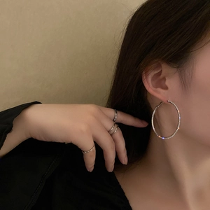 Silver needle hoop earrings with pavé crystals on model with minimalist rings