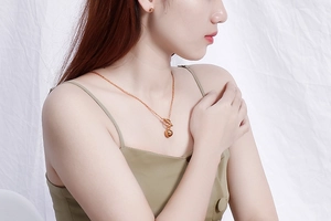 Model wearing a gold ball bead necklace with OT toggle clasp and matching stud earrings