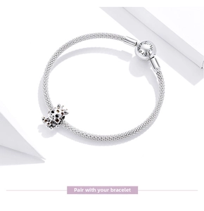 Macro detail of silver mesh bracelet with cute giraffe charm and engraved ball clasp