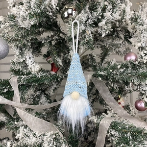 Blue knit Christmas gnome ornament with sequins hanging on a decorated tree