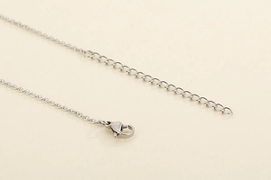 Detailed macro view of silver stainless steel necklace chain with lobster clasp and extender