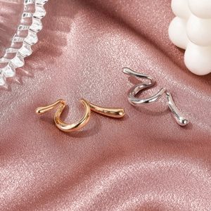 Sleek punk style snake ear cuffs in gold and silver finish on purple satin background