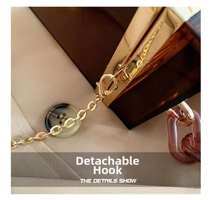 Detail of the golden metal lobster clasp with pink acrylic and gold chain strap links